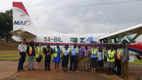 MAF Uganda's staff gathered between the wings of Cessna 208 Caravan for the last time