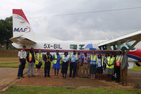 MAF Uganda's staff gathered between the wings of Cessna 208 Caravan for the last time