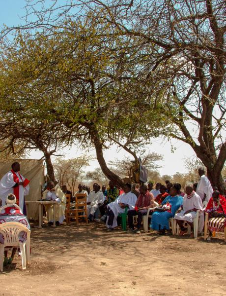Baptism service taking plave under the slim shade of acasia tree.